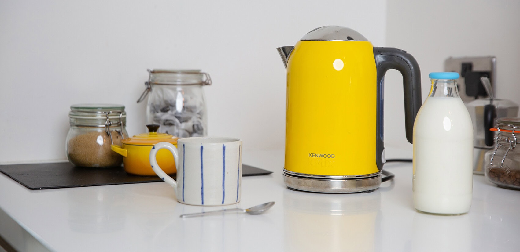 Yellow kettle on a work surface, with a mug next to it.